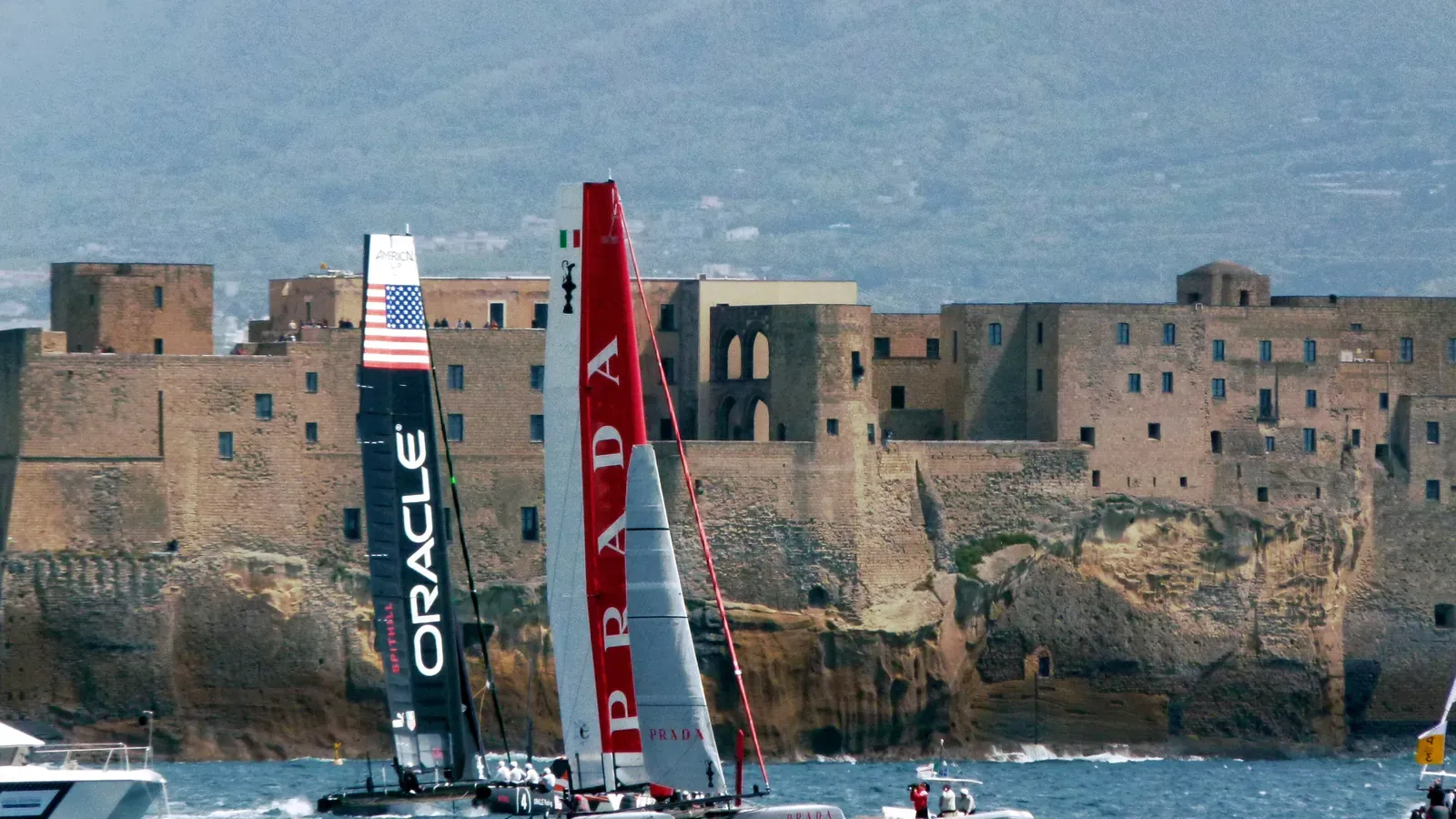 Oracle and Luna Rossa catamarans racing past Castel dell'Ovo at the 2012 America's Cup World Series in Naples