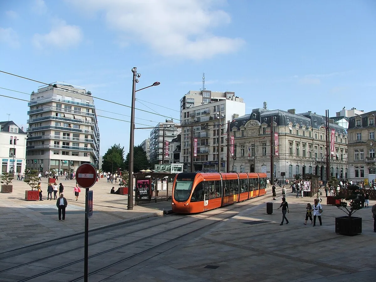 An orange Le Mans tram crossing the paved Place de la République in the city centre
