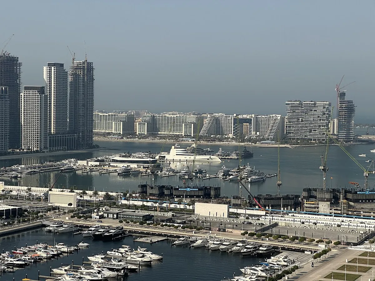Superyachts and smaller boats moored in a Dubai marina below waterfront towers