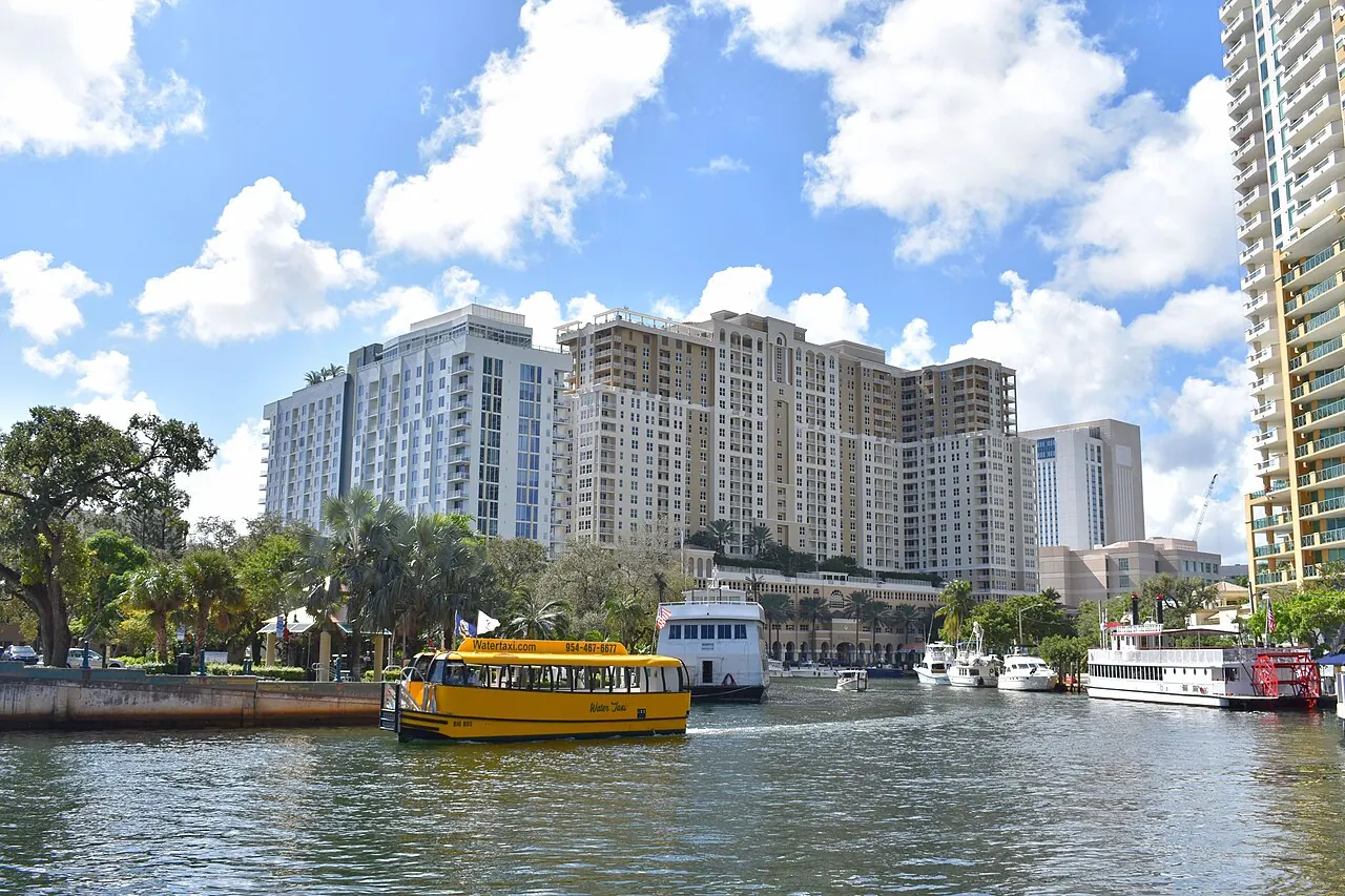 A yellow Fort Lauderdale Water Taxi on the river in front of high-rise buildings