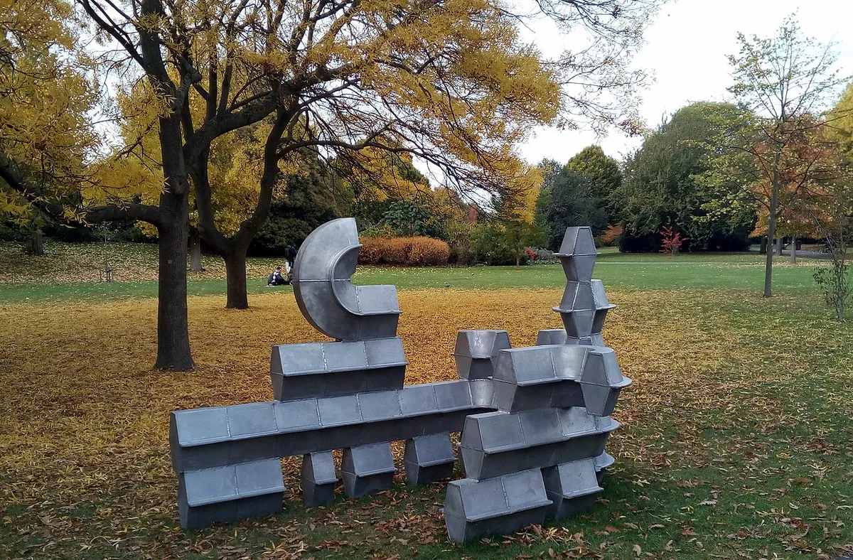 A silver abstract sculpture on the grass among autumn trees in Regent's Park