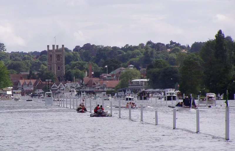 Rowing crews racing down the booms of the Henley course towards the church tower and town