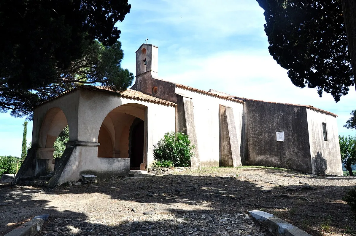 The small white Chapelle Sainte-Anne with its bell tower among pine trees