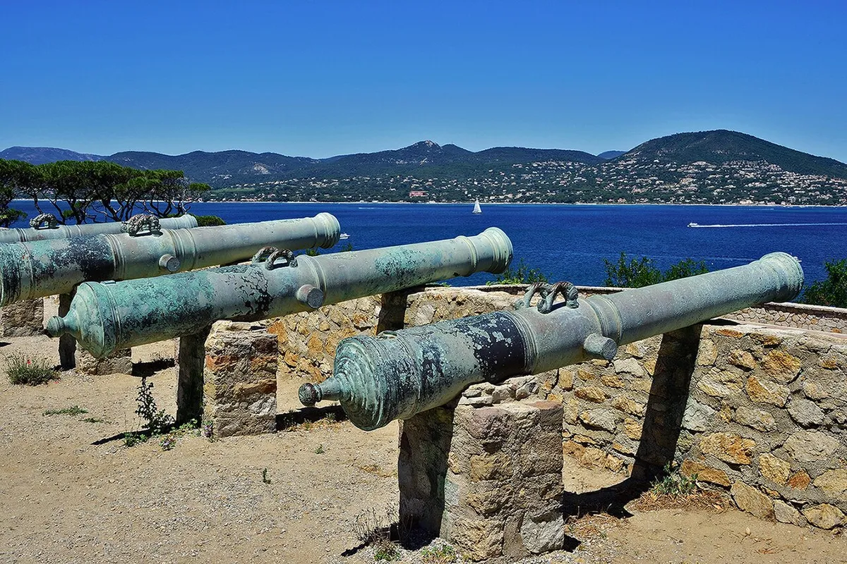 Old bronze cannons on stone mounts at the Citadelle looking out over the blue gulf and hills