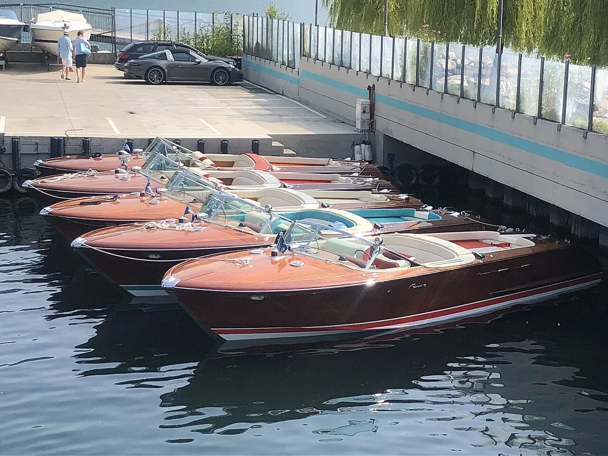 A row of varnished wooden Riva runabouts moored side by side