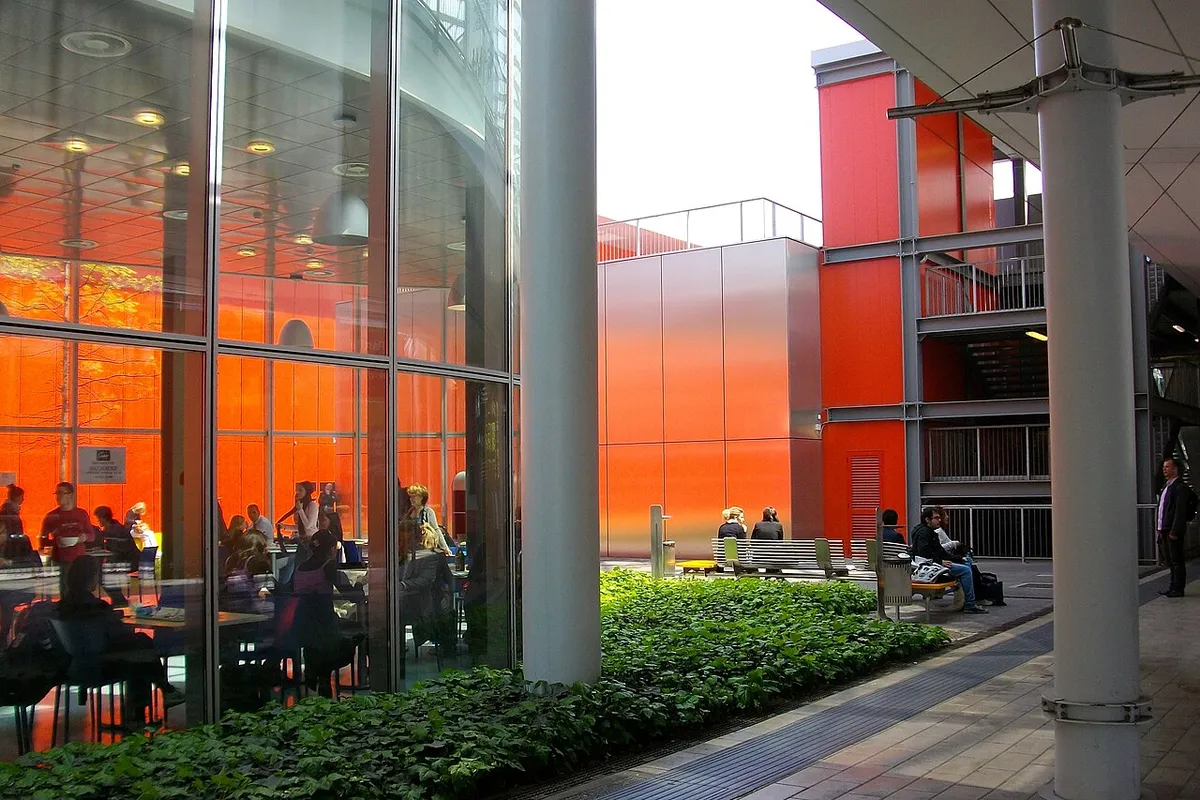 Glass and bright orange pavilion walls at the Fiera Milano exhibition centre in Rho, with visitors at tables