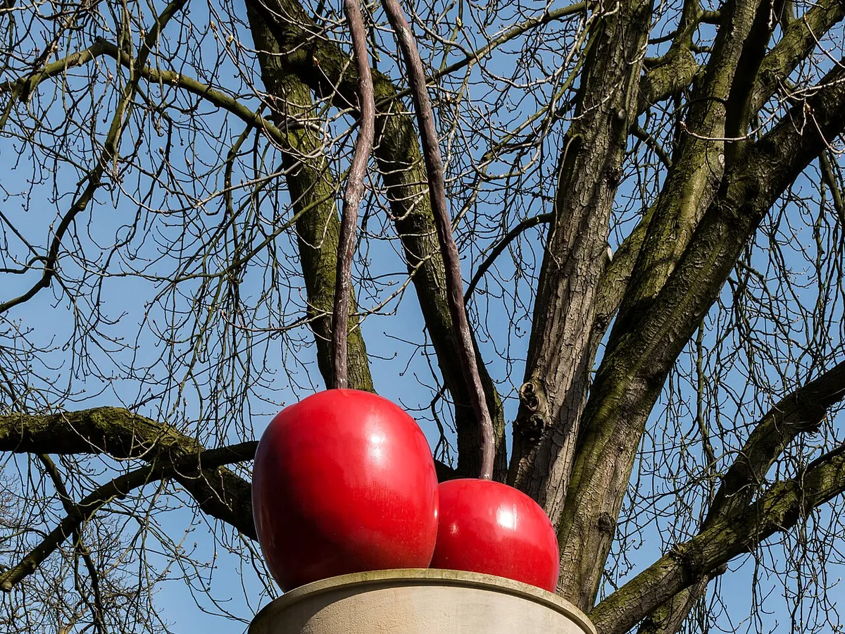 Thomas Schütte's sculpture of two giant red cherries on a stone column against bare trees