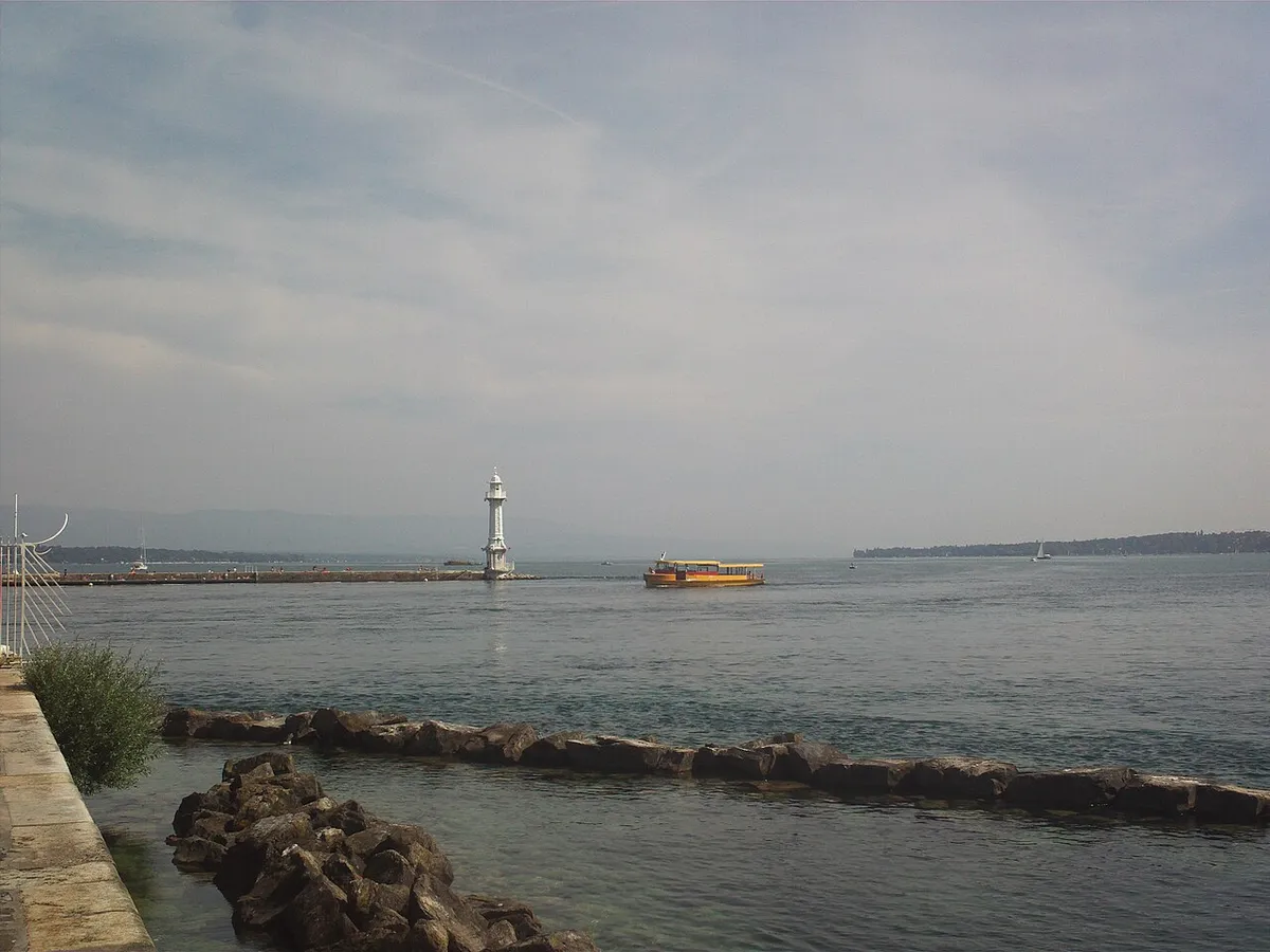 Lake Geneva seen from the shore, with a small yellow Mouette passenger boat crossing the water