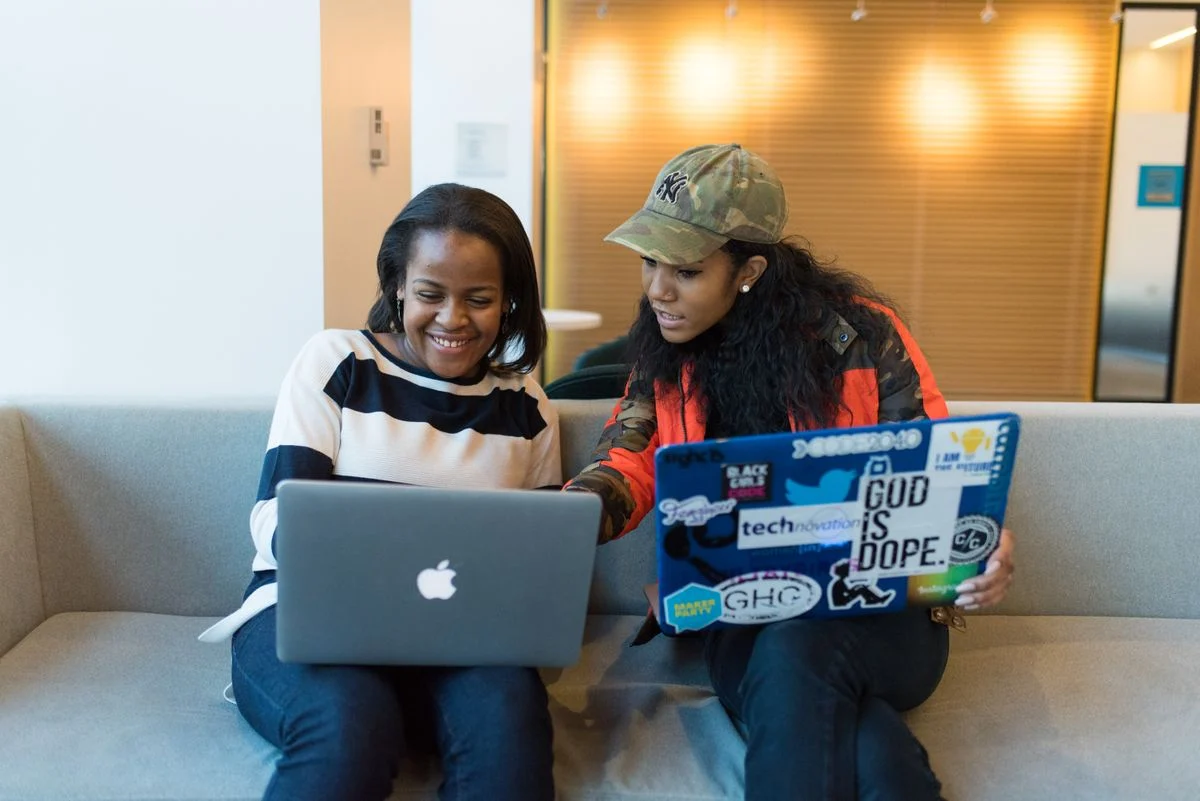 Two women collaborating on laptops